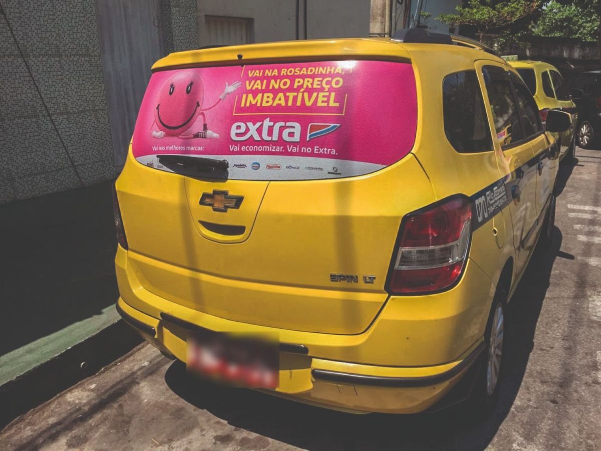 Táxi amarelo no Rio de Janeiro com publicidade Taxidoor do Extra no vidro traseiro